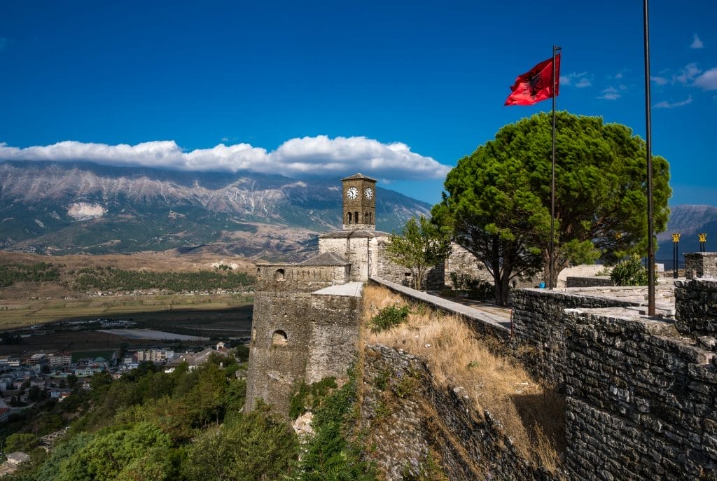 Clock Tower with waving Albanian flag in Gjirokaster Citadel or castle attraction in Albania, Europe